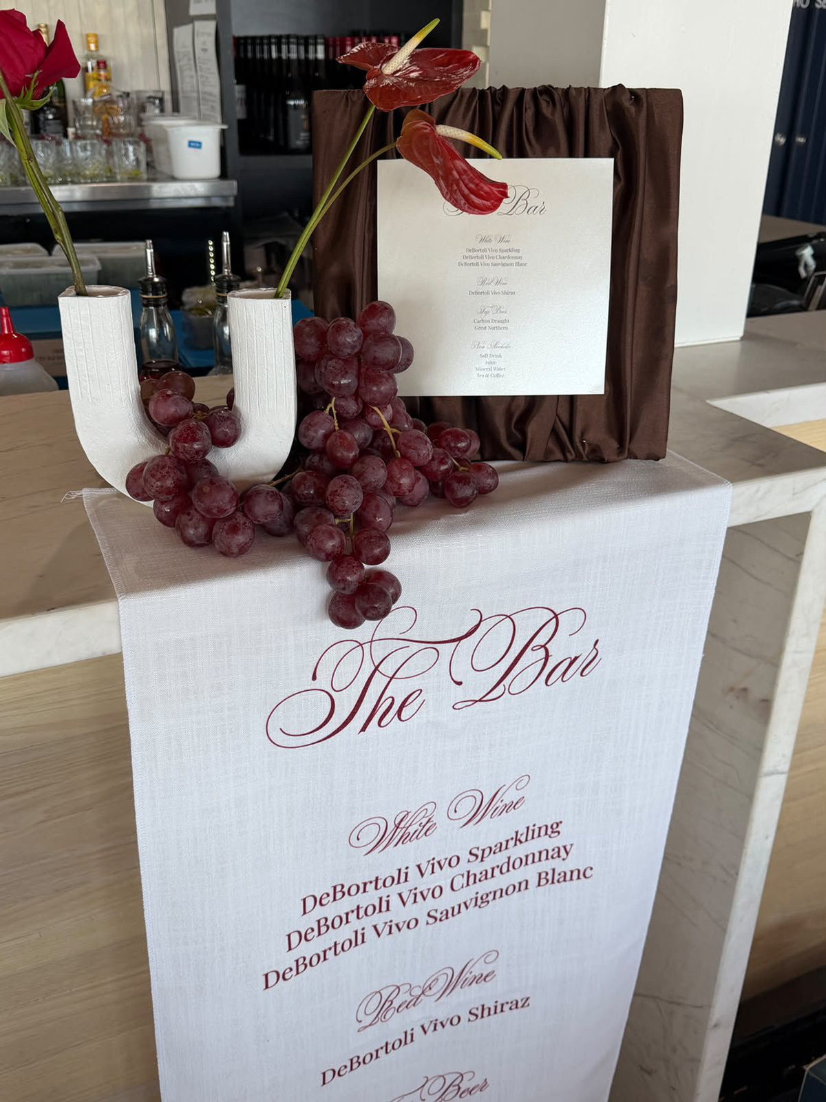 Fabric Bar Sign: linen The Bar menu runner on a bar with grapes and anthuriums