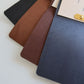 Black, brown, tan and navy leather menus fanned with an insert
